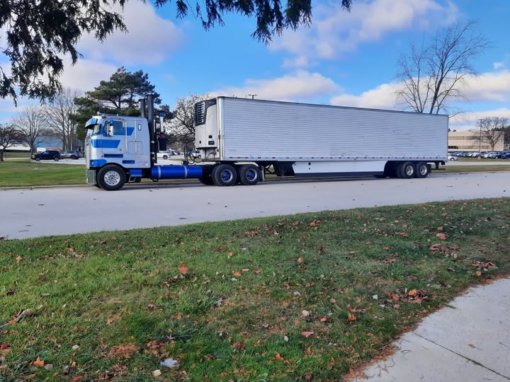 Blue and white cabover tractor with refrigerated trailer