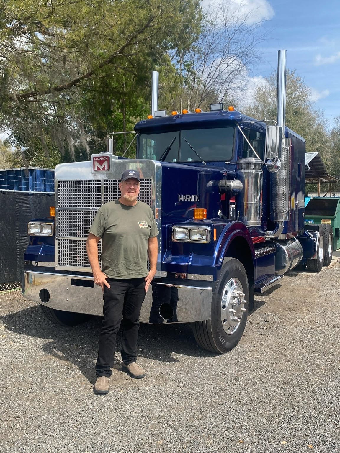 Owner operator standing in front of a blue Marmon conventional tractor